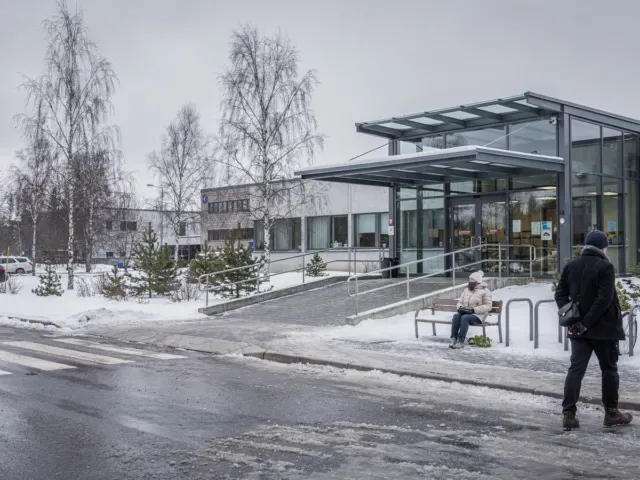 Nykyaikaisen sairaalakampuksen sisäänkäynti talvella, esteetön ramppi ja pysäköinti.